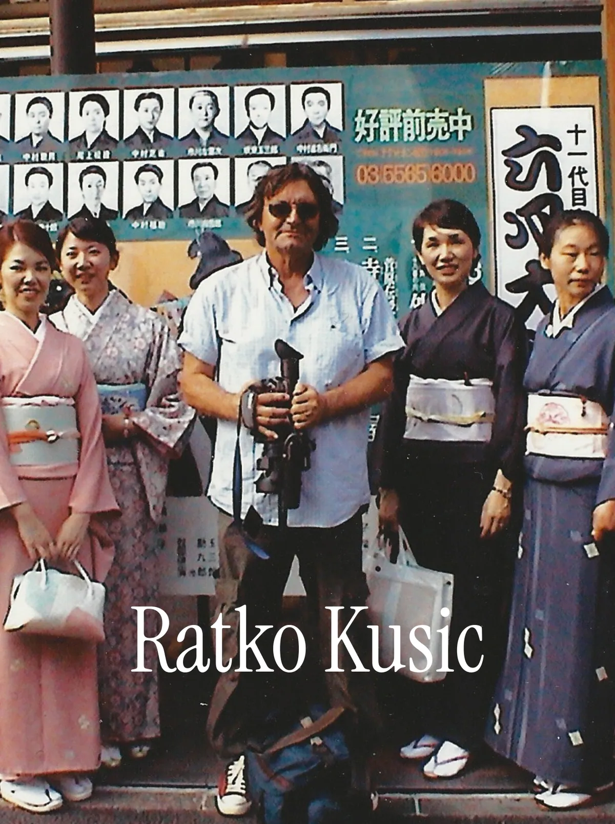 Ratko Kušić key visual: an archival photograph of the cameraman holding his camera beside women in kimono on a Kyoto street, with the Ratko Kusic wordmark below.